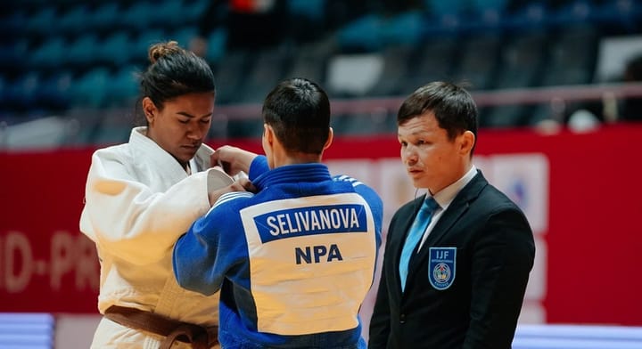 À esquerda, Kelly posiciona sua pegada em Kristina Selivanova observada pelo árbitro do combate.